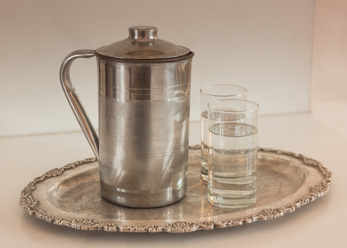 A silver water jug and glass